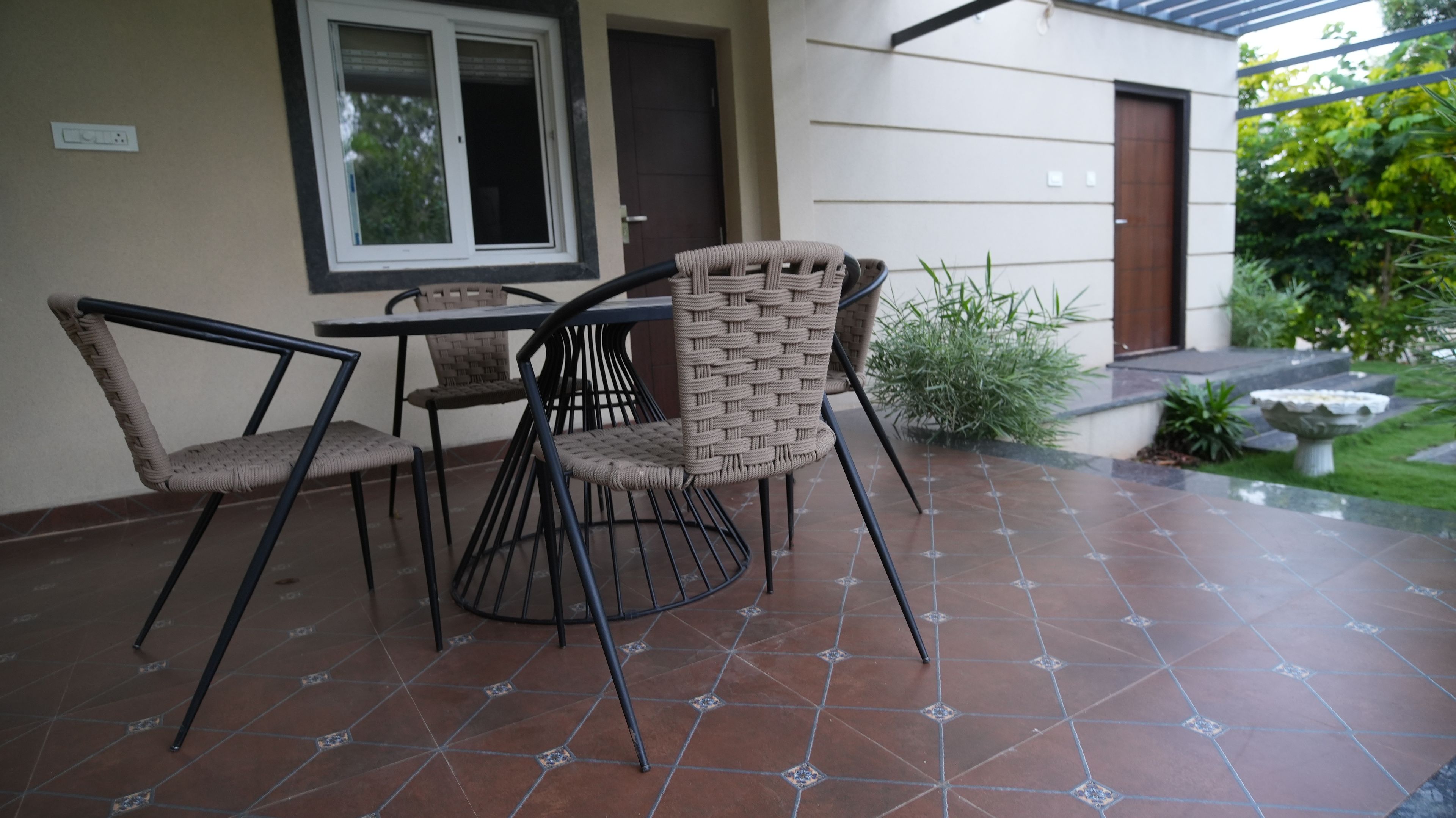 An outdoor patio with a table and chairs, a tiled floor, and a door in the background.