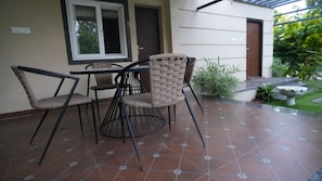 An outdoor patio with a table and chairs, a tiled floor, and a door in the background.