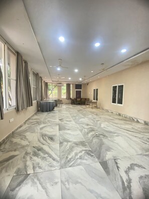 A spacious room with a marble floor, ceiling fans, and a dining area with tables and chairs.