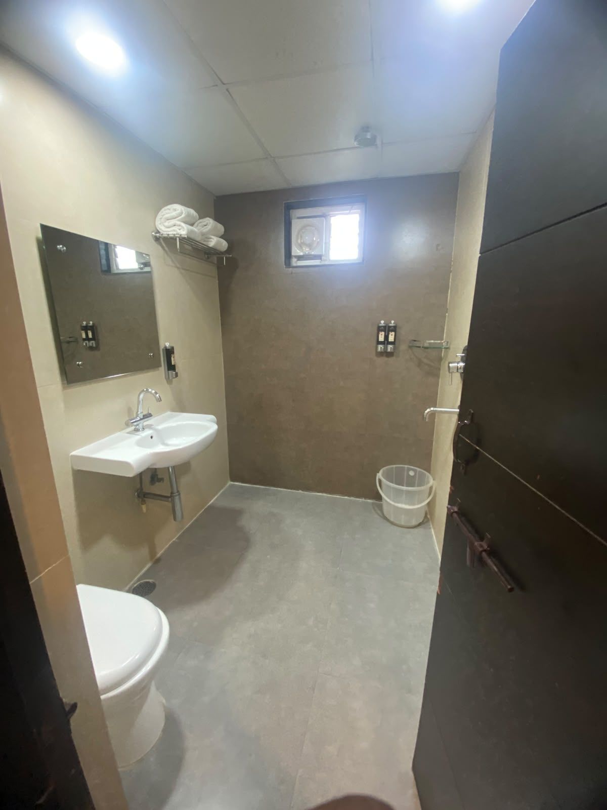 A bathroom with a white sink, a toilet, a mirror, and a shower area.