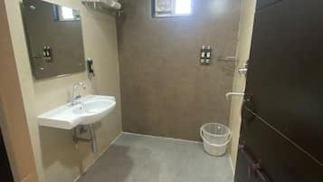 A bathroom with a white sink, a toilet, a mirror, and a shower area.