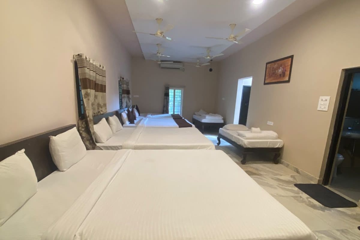 A hotel room with two beds, a ceiling fan, and a view of the outside.