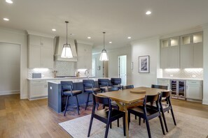 A modern kitchen with a central island, bar stools, and pendant lighting.