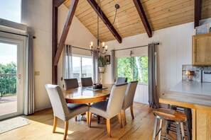 Ein Essbereich mit Holztisch und Stühlen, einer Chandelierleuchtre und Blick ins Freie.