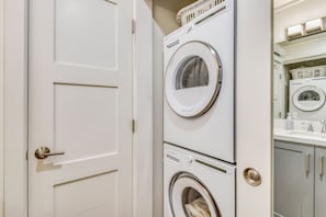 Uma lavanderia com duas máquinas de lavar roupa empilhadas e uma porta.