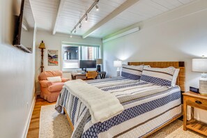 Ein Schlafzimmer mit einem großen Bett, einem Schreibtisch, einem Stuhl und einem Fernseher.