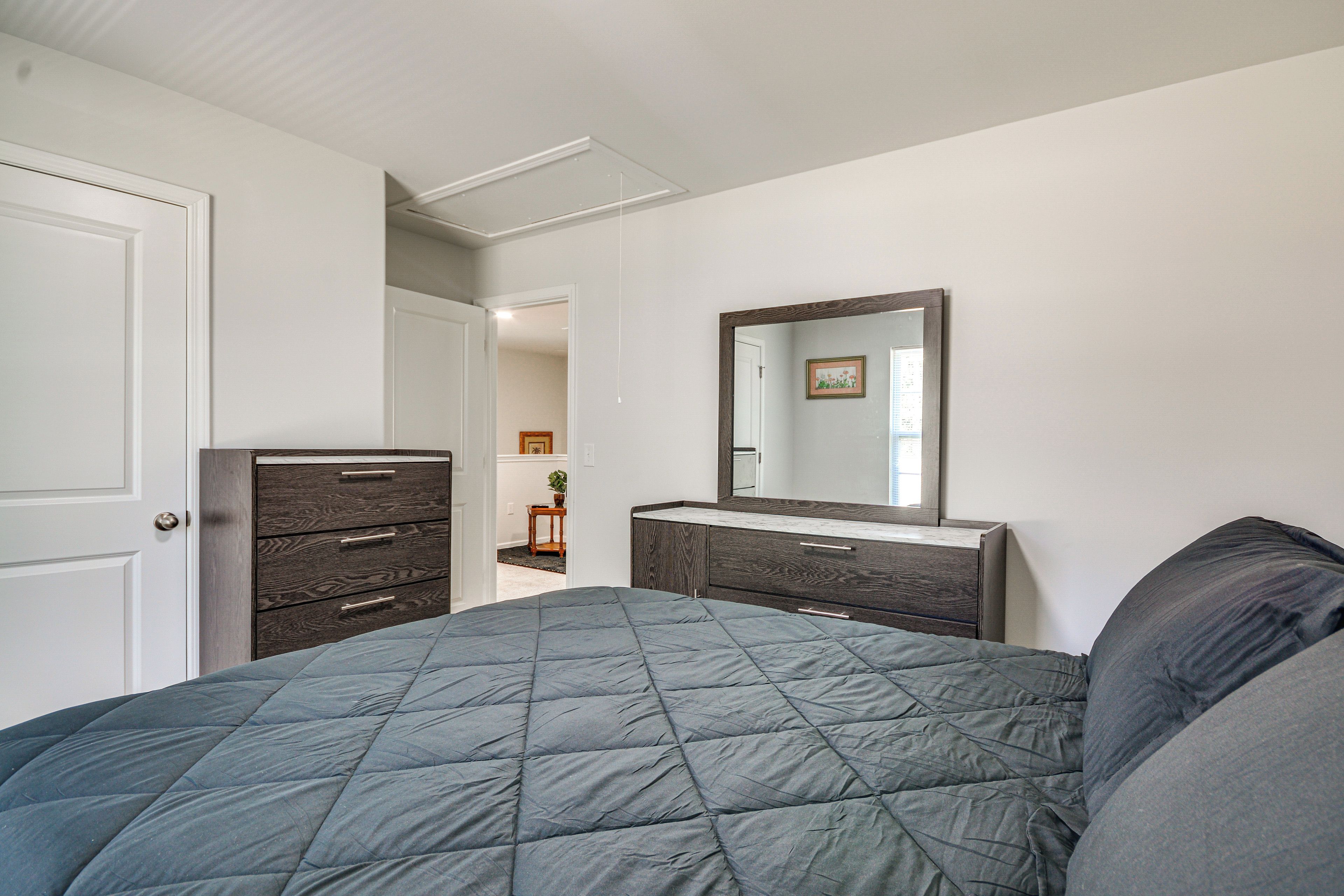 A bedroom with a bed, dresser, and mirror.