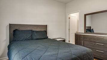 A bedroom with a bed, a dresser, and a mirror.