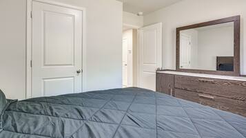 A bedroom with a bed, a dresser, and a mirror.