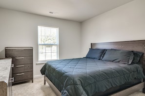 Een slaapkamer met een bed, een kast en een raam.