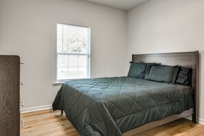 A bedroom with a bed, a window, and a door.