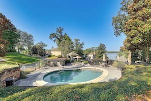 A residential property with a swimming pool, outdoor furniture, and a view of a lake.