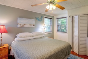 A bedroom with a bed, a nightstand, a lamp, a ceiling fan, a window with blinds, and a door. - 2 Mi to Dtwn Pensacola: Historic Home w/ Patio! (Pensacola)