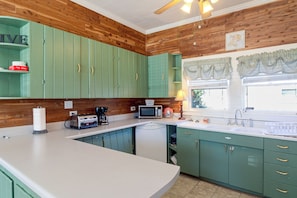 A kitchen with green cabinets, a white countertop, and a window with curtains. - 2 Mi to Dtwn Pensacola: Historic Home w/ Patio! (Pensacola)