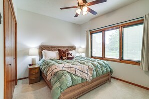 A bedroom with a bed, nightstand, lamp, window, and ceiling fan.