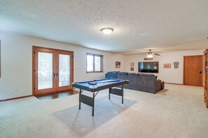A living room with a pool table, a gray sofa, a television, and a ceiling fan.