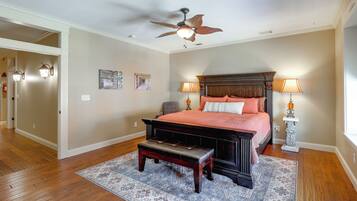A bedroom with a bed, a bench, a ceiling fan, two wall-mounted lamps, and a rug.