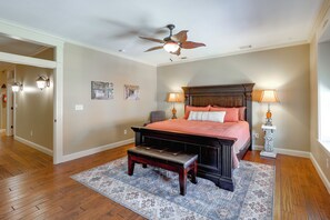 A bedroom with a bed, a bench, a ceiling fan, two wall-mounted lamps, and a rug.