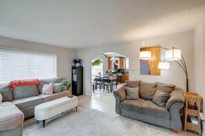 A living room with a sofa, a bench, and a dining area with a table and chairs. - Seaside Monthly Rental Across From Martin Park (Seaside)