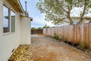 A backyard with a wooden fence, a tree, and a gravel path. - Seaside Monthly Rental Across From Martin Park (Seaside)