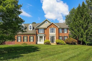 A two-story brick house with a front porch, a garage, and a well-maintained lawn. - Spacious Bowie Home Near D.C. Attractions (Bowie)