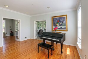 Une pièce spacieuse dotée d’un parquet, d’un grand piano et d’un tableau de grande taille accroché au mur.