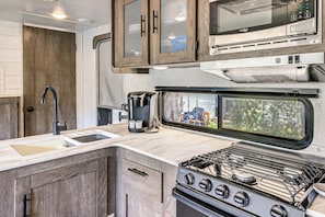 A compact kitchen with a built-in stove, a coffee maker, and a microwave.
