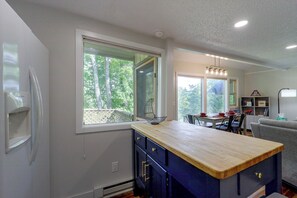 A kitchen with a wooden island, a dining area with a table set for two, and a view of the outdoors through large windows. - 3 Blocks to the Slopes! Sugar Mtn Ski Condo (Sugar Mountain)
