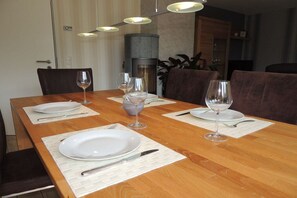 A dining table set with plates, cutlery, and wine glasses, with chairs around it. - Holiday apartment in Sylt with swimming pool (Sylt)