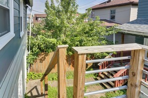 A wooden deck with a metal ladder, surrounded by greenery and residential buildings. - Nurse-Ready Rental 1 Mi to Franciscan University! (Steubenville)