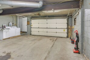 A garage with a closed garage door, a washing machine, and a red floor scrubber. - Nurse-Ready Rental 1 Mi to Franciscan University! (Steubenville)