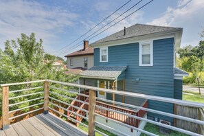 A two-story house with a wooden deck and a metal railing.