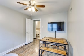 A room with a ceiling fan, a television mounted on the wall, and a wooden table with two remote controls on it. - Nurse-Ready Rental 1 Mi to Franciscan University! (Steubenville)