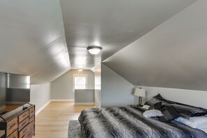 A bedroom with a bed, dresser, and a ceiling light.