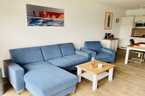 A living room with a blue sofa, a wooden coffee table, and a painting on the wall. - Duhner Allee 10, "Litfaß 17" (Cuxhaven)