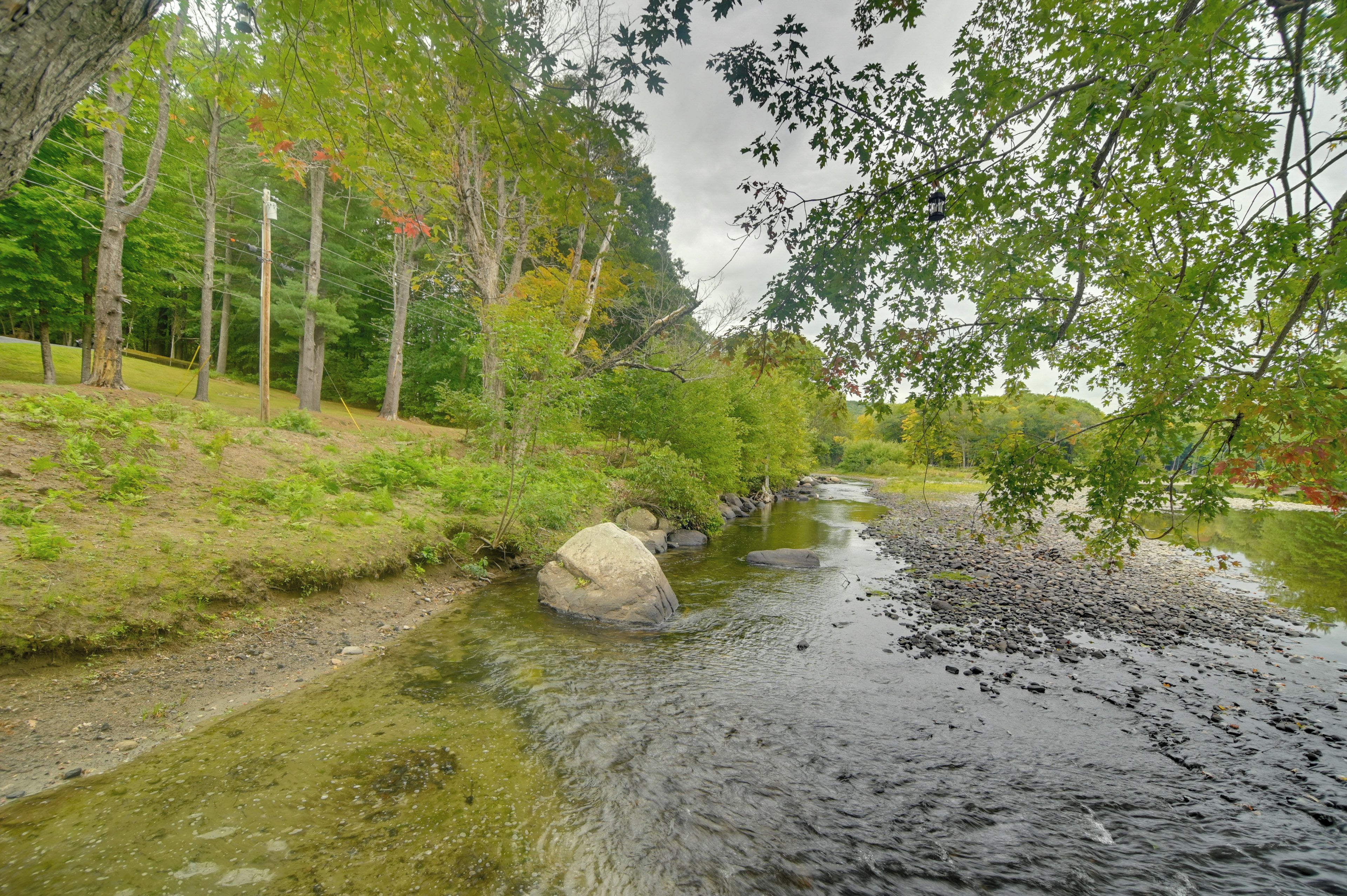 Une rivière dont les berges sont bordées de rochers et d’arbres.