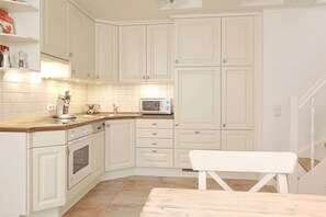 A kitchen with white cabinetry, a microwave, and a wooden countertop. - Sonnenkuhle - Ameland 09 (Wenningstedt - Braderup)