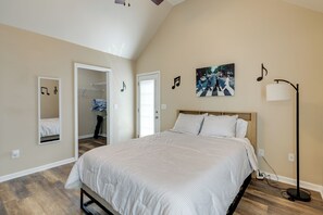 A bedroom with a bed, a wardrobe, a mirror, a picture on the wall, and a floor lamp. - Minutes From Grand Ole Opry! River Retreat (Nashville)