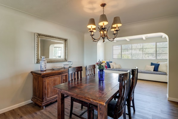 Un comedor con mesa de madera, sillas, un candelabro, un espejo y una ventana con vistas.