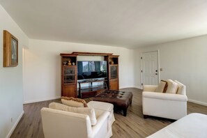 Una sala de estar con televisor, dos sofás y un mueble bajo de madera.