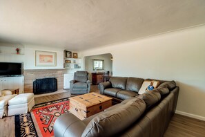 A living room with a leather sofa, a wooden coffee table, a fireplace, and a television. - Pool, Putting Green & Mtn Views: Tucson Home (Tucson)