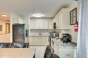 Eine moderne Küche mit weißen Schränken, einem Edelstahlkühlschrank, einer Kaffeemaschine und einem Toaster.