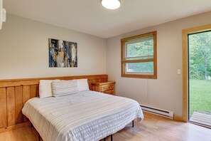Ein Schlafzimmer mit einem Bett, einem Nachttisch, einem Fenster und einem Bild an der Wand.