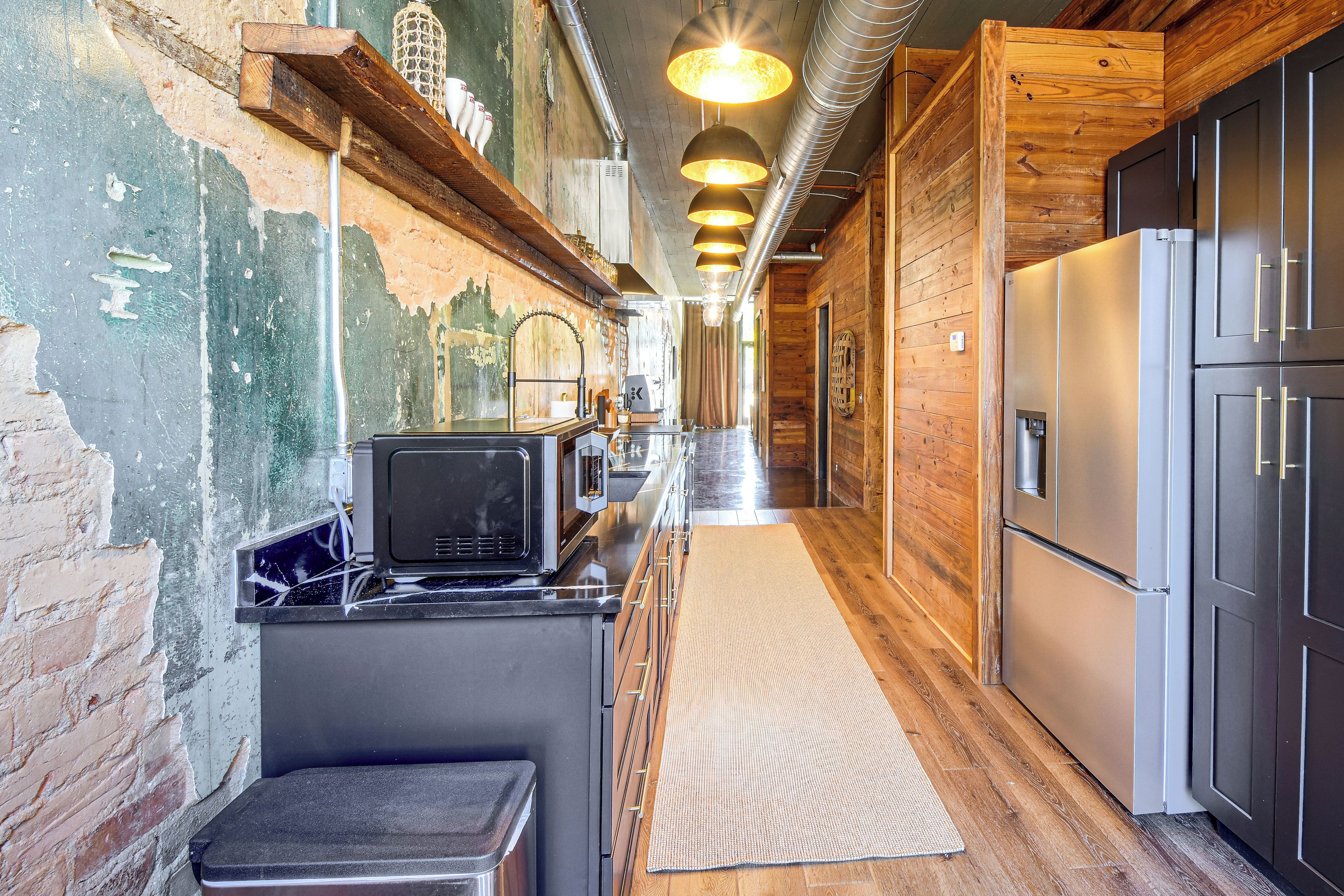 A narrow kitchen with wooden walls, a stainless steel refrigerator, and a built-in stove.
