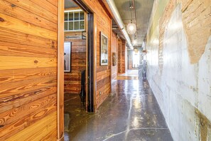 A wooden hallway with a polished floor, a door leading to a room, and a window with a view.