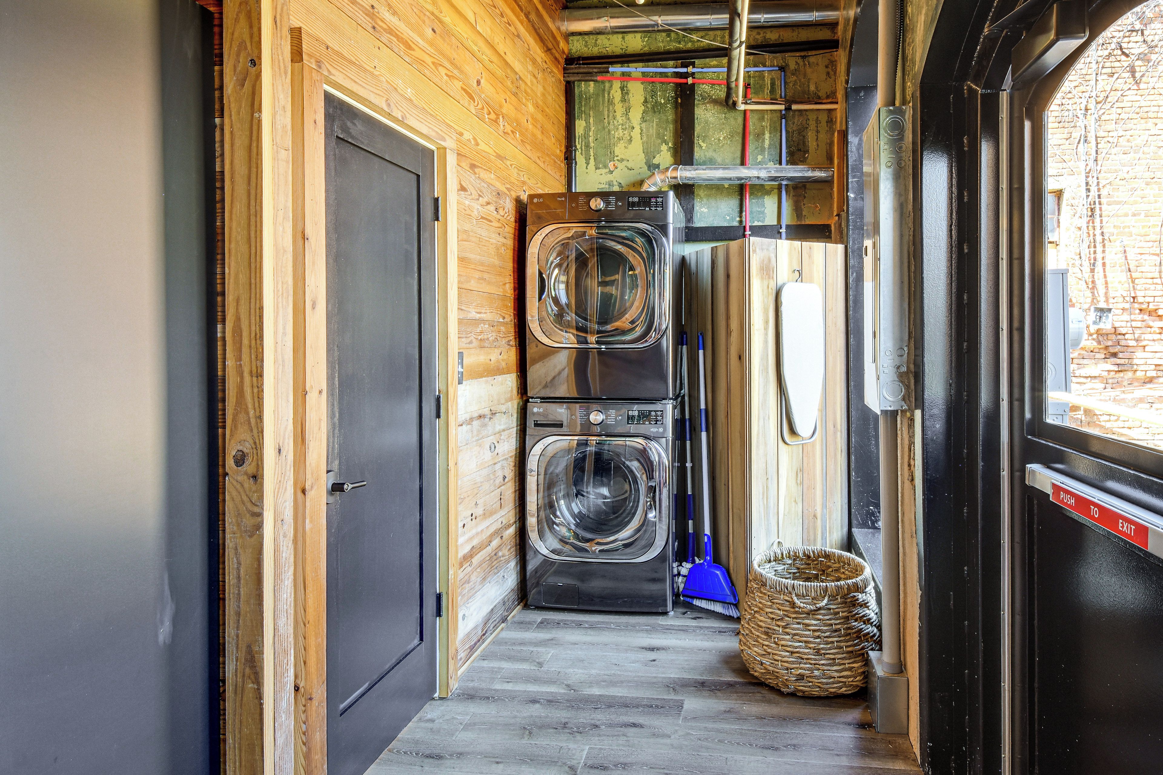 A laundry area with two stacked washers and dryers, a metal door, and a wooden wall.