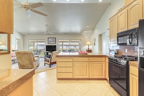 A spacious kitchen with a central island, a dining area with a sofa and chairs, and a view through the glass doors. - Panoramic Views! Clear Lake Cottage w/ Patio (Clearlake)