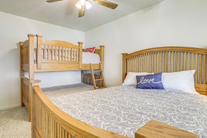 A bunk bed with a ladder, a single bed with a patterned bedspread, and a ceiling fan. - Panoramic Views! Clear Lake Cottage w/ Patio (Clearlake)