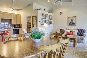 A dining area with a wooden table and chairs, a potted plant, and a kitchen in the background. - Panoramic Views! Clear Lake Cottage w/ Patio (Clearlake)
