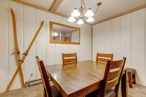 A dining room with a wooden table, four chairs, a mirror, and a chandelier. - Steps to Slopes! Mammoth Mountain Condo (Mammoth Lakes)